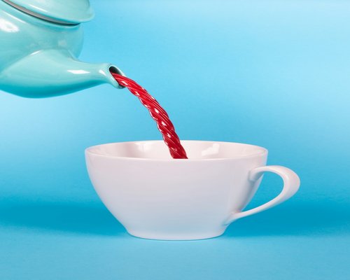 Pouring hot ginger tea into a ceramic mug