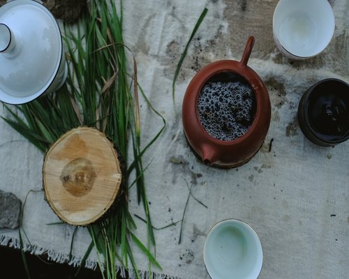 Fresh lemongrass stalks tied together next to a teacup